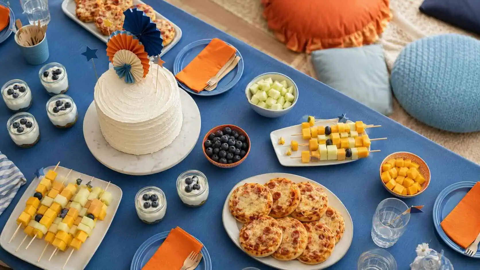 Mesa de cumpleaños temática Bluey con paleta azul y naranja — mini pizzas, brochetas de fruta y tarta sencilla